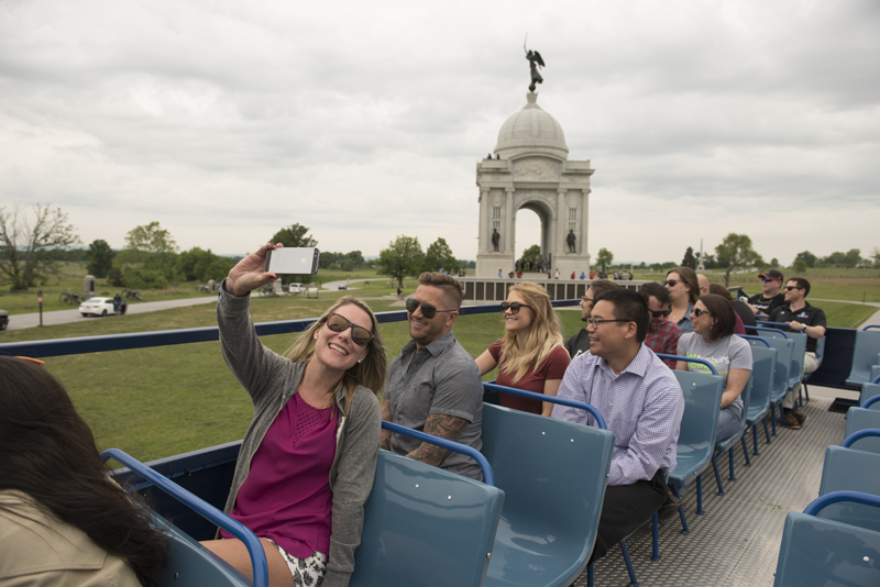 a woman taking a selfie on top of a gettysburg double decker bus